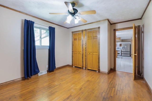 3047 S Ferguson Ave, Springfield, MO 65807 - unfurnished bedroom with stainless steel fridge, light wood-type flooring, crown molding, a textured ceiling, and ceiling fan