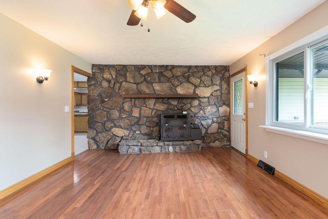 3047 S Ferguson Ave, Springfield, MO 65807 - unfurnished living room with wood finished floors, heating unit, ceiling fan, and a wood stove