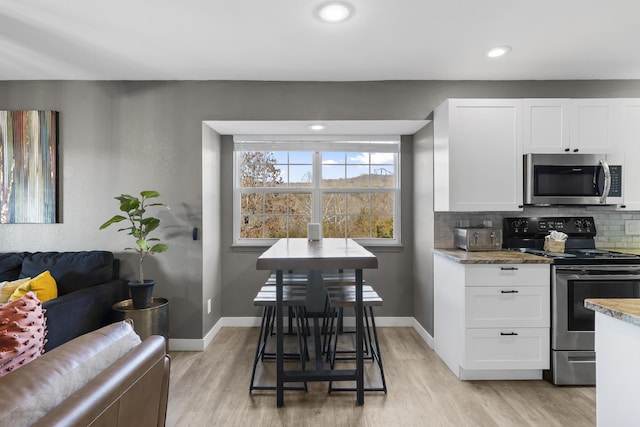 kitchen featuring appliances with stainless steel finishes, light wood-type flooring, white cabinetry, decorative backsplash, and recessed lighting