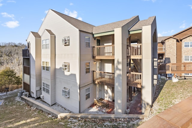 view of side of home with a balcony and a shingled roof