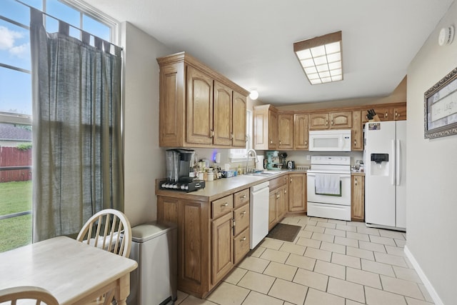 1925 Sylvan Ave, Neosho, MO 64850 - kitchen featuring white appliances, light countertops, light tile patterned flooring, and brown cabinets