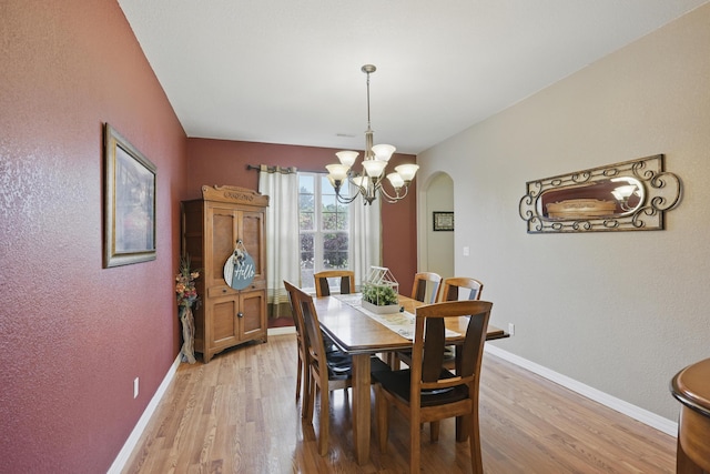 1925 Sylvan Ave, Neosho, MO 64850 - dining area with a chandelier, light wood-style flooring, arched walkways, and a textured wall