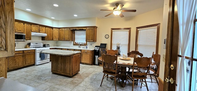 3889 E State Highway Kk, Fair Grove, MO 65648 - kitchen featuring white gas range, under cabinet range hood, stainless steel microwave, a center island, and a ceiling fan