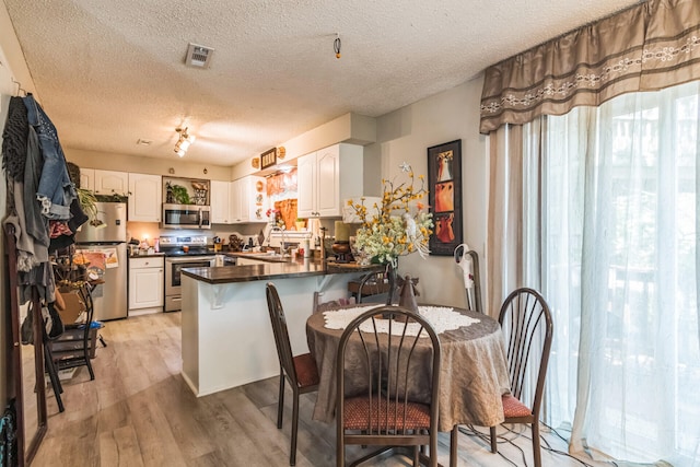 426 Lakewood Rd, Branson, MO 65616 - kitchen with appliances with stainless steel finishes, a peninsula, dark countertops, light wood finished floors, and white cabinetry