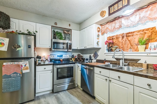426 Lakewood Rd, Branson, MO 65616 - kitchen with stainless steel appliances, light wood finished floors, white cabinetry, a textured ceiling, and butcher block countertops