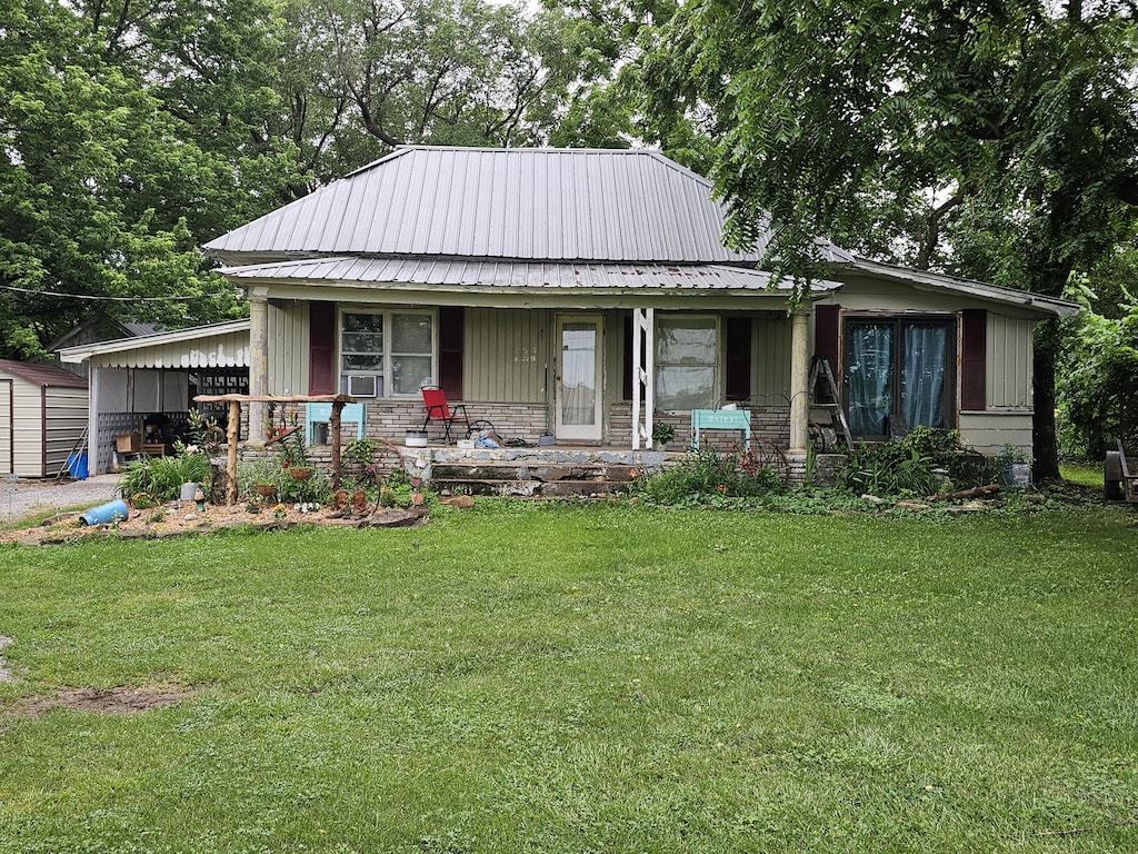 502 S Gilman Ave, Wheaton, MO 64874 - view of front of home with covered porch, a front lawn, a metal roof, a shed, and board and batten siding
