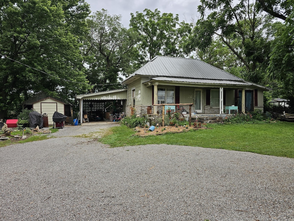 502 S Gilman Ave, Wheaton, MO 64874 - view of front of house with a porch, driveway, a carport, a front yard, and a shed