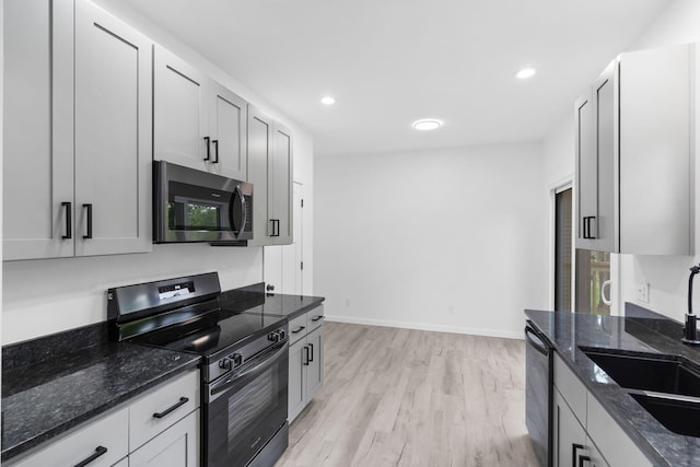 804 Iris Ave, Crane, MO 65633 - kitchen featuring stainless steel microwave, black / electric stove, dishwasher, light wood finished floors, and dark stone counters