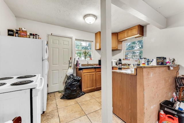 1673 E Chestnut St, Springfield, MO 65802 - kitchen featuring light tile patterned flooring, white electric range, brown cabinetry, and a textured ceiling