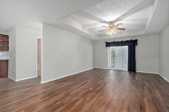2606 S Overbrook Ave, Springfield, MO 65807 - unfurnished living room featuring a raised ceiling, ceiling fan, dark wood-style floors, and a textured ceiling