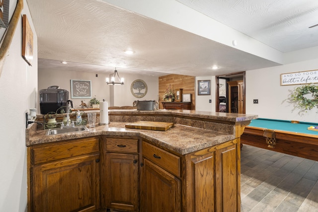 417 Panorama Dr, Cape Fair, MO 65624 - kitchen with a peninsula, brown cabinetry, wood finished floors, a chandelier, and dark countertops