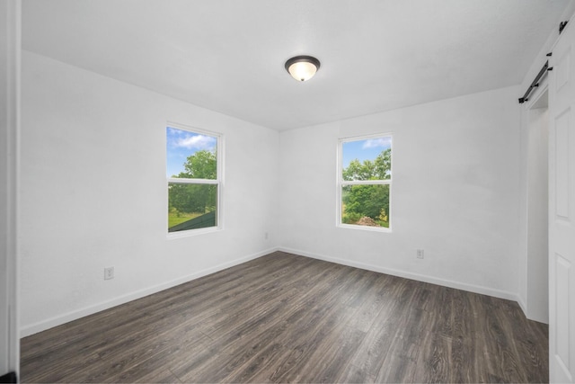 503 Valley View St, Carl Junction, MO 64834 - unfurnished bedroom featuring a barn door, multiple windows, and dark wood-type flooring