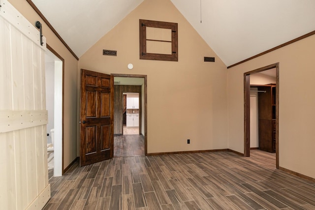 311 College St, Crane, MO 65633 - unfurnished living room featuring dark wood finished floors, high vaulted ceiling, and a barn door