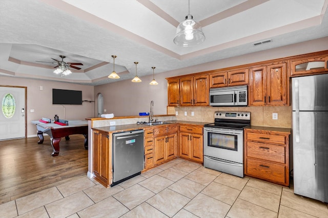 107 W Summit St, Aurora, MO 65605 - kitchen featuring appliances with stainless steel finishes, a raised ceiling, ceiling fan, brown cabinets, and a peninsula