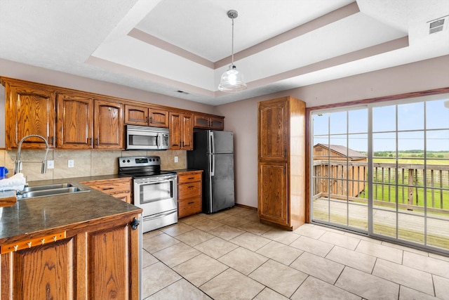 107 W Summit St, Aurora, MO 65605 - kitchen with stainless steel appliances, a raised ceiling, brown cabinetry, tasteful backsplash, and dark countertops