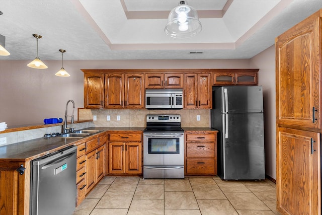 107 W Summit St, Aurora, MO 65605 - kitchen featuring stainless steel appliances, brown cabinets, dark countertops, and a peninsula