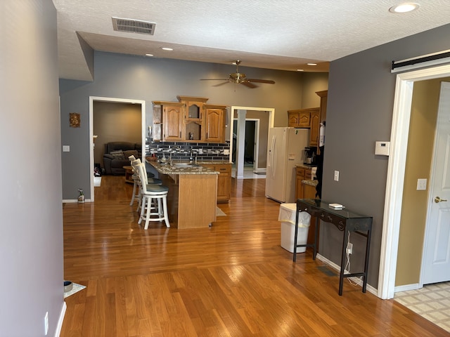 4849 W Rose Hill Rd, Billings, MO 65610 - kitchen with white fridge with ice dispenser, a peninsula, a breakfast bar, open shelves, and ceiling fan