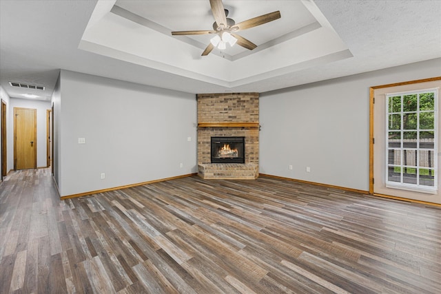 951 S Alex Ave, Springfield, MO 65802 - unfurnished living room featuring a tray ceiling, wood finished floors, ceiling fan, and a brick fireplace
