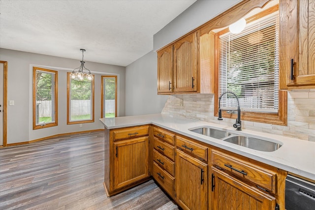 951 S Alex Ave, Springfield, MO 65802 - kitchen with a peninsula, light countertops, wood finished floors, decorative backsplash, and hanging light fixtures