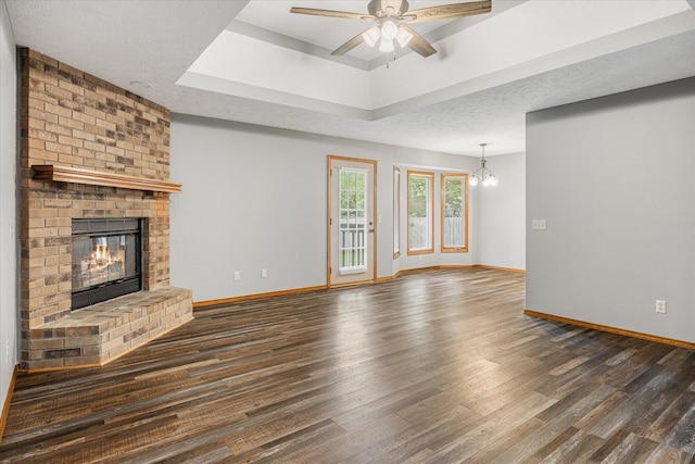 951 S Alex Ave, Springfield, MO 65802 - unfurnished living room featuring wood finished floors, a fireplace, a ceiling fan, a raised ceiling, and a chandelier