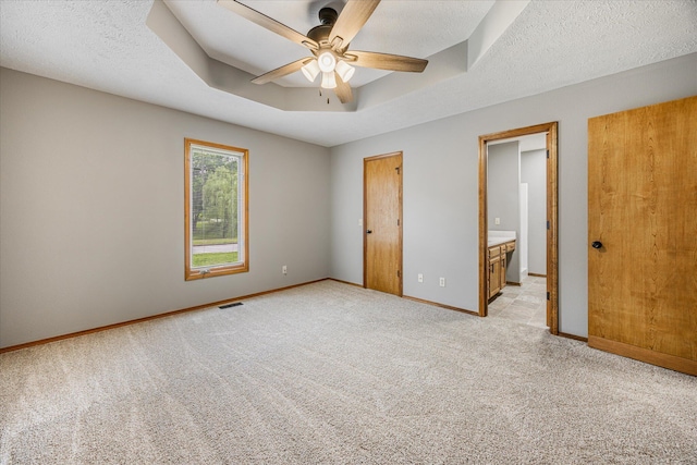 951 S Alex Ave, Springfield, MO 65802 - unfurnished bedroom featuring light carpet, a raised ceiling, connected bathroom, and a ceiling fan