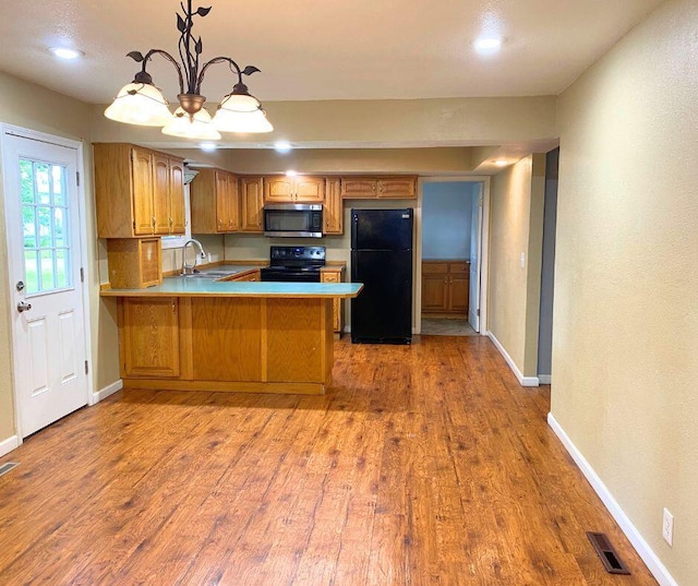106 Cooley Dr, Carl Junction, MO 64834 - kitchen featuring black appliances, brown cabinetry, wood finished floors, a peninsula, and recessed lighting