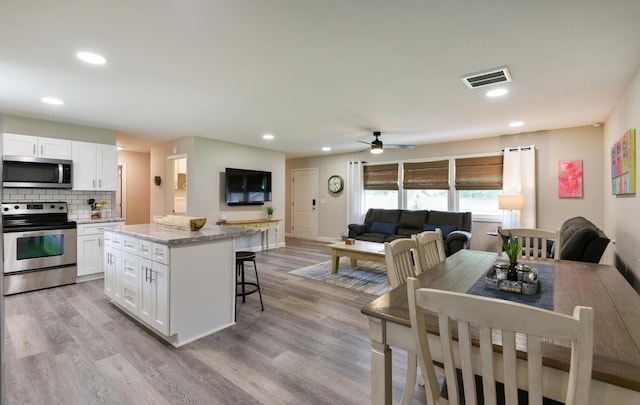 2823 E Catalpa St, Springfield, MO 65804 - kitchen featuring stainless steel appliances, a center island, white cabinetry, a kitchen bar, and backsplash