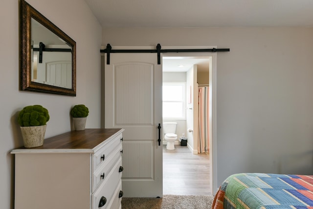 2823 E Catalpa St, Springfield, MO 65804 - bedroom featuring wood finished floors, a barn door, and ensuite bathroom