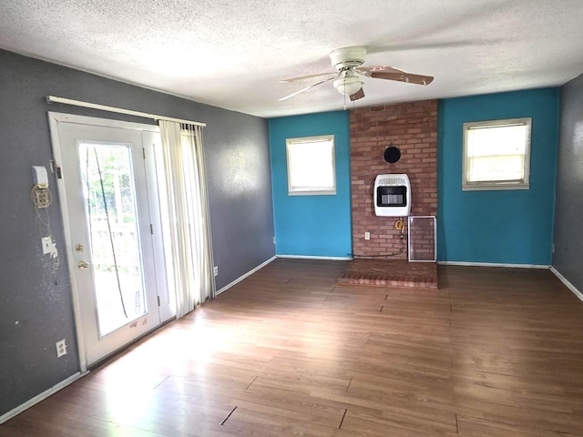 306 S Locust St, Buffalo, MO 65622 - unfurnished living room with heating unit, a ceiling fan, a textured ceiling, plenty of natural light, and wood finished floors