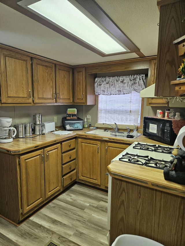462 Jellystone Ave, Hollister, MO 65672 - kitchen featuring black microwave, light wood finished floors, light countertops, and brown cabinetry