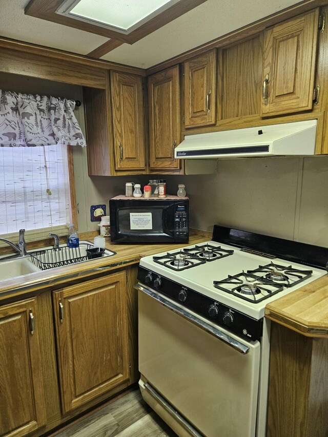 462 Jellystone Ave, Hollister, MO 65672 - kitchen with white range with gas stovetop, black microwave, under cabinet range hood, and brown cabinets