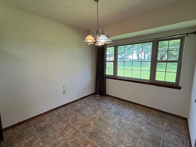 2604 Country Dr, Mountain Grove, MO 65711 - empty room featuring a chandelier, a textured ceiling, and stone finish floors