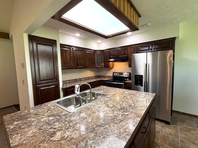 2604 Country Dr, Mountain Grove, MO 65711 - kitchen with appliances with stainless steel finishes, under cabinet range hood, dark brown cabinets, recessed lighting, and a center island with sink