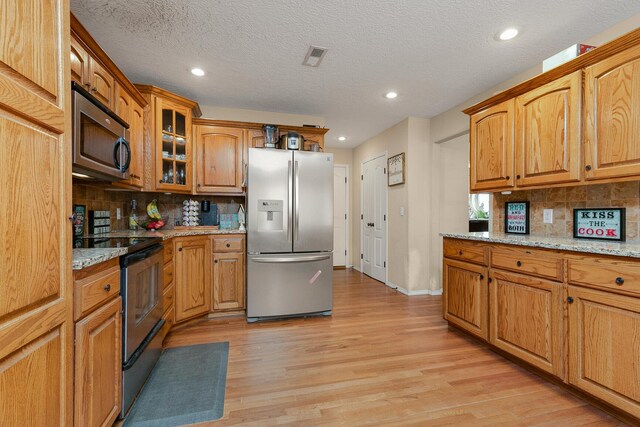 3223 W Melbourne St, Springfield, MO 65810 - kitchen with stainless steel appliances, light wood-style floors, tasteful backsplash, recessed lighting, and glass insert cabinets