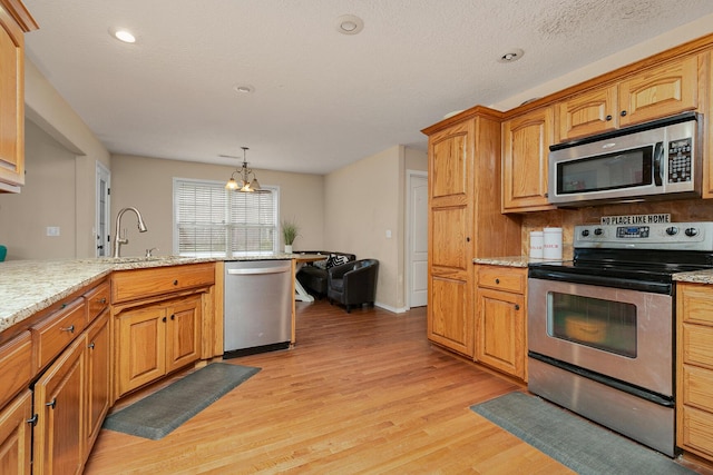 3223 W Melbourne St, Springfield, MO 65810 - kitchen featuring stainless steel appliances, light wood-style flooring, a chandelier, light stone countertops, and recessed lighting