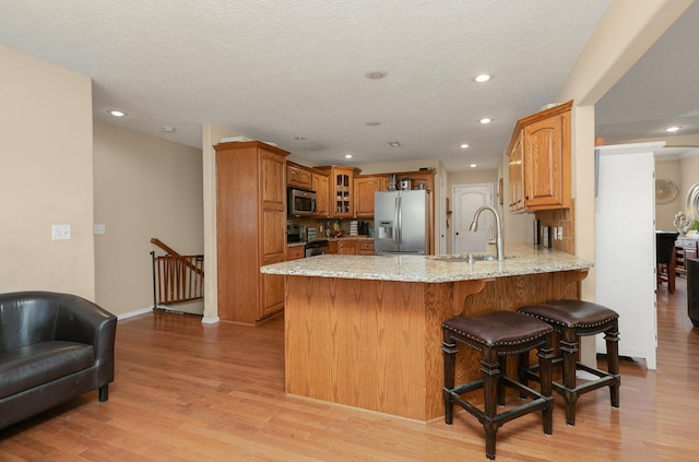 3223 W Melbourne St, Springfield, MO 65810 - kitchen with appliances with stainless steel finishes, a peninsula, glass insert cabinets, recessed lighting, and light stone counters