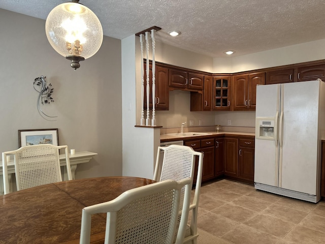 3454 W Countryside Dr, Springfield, MO 65807 - kitchen featuring white refrigerator with ice dispenser, glass insert cabinets, a textured ceiling, light countertops, and decorative light fixtures