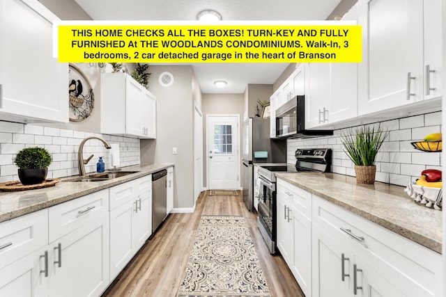 280 W Woodland Dr Unit Ld, Branson, MO 65616 - kitchen featuring appliances with stainless steel finishes, white cabinetry, light wood-style flooring, backsplash, and light stone counters