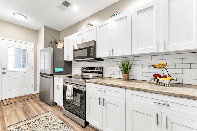 280 W Woodland Dr Unit Ld, Branson, MO 65616 - kitchen with stainless steel appliances, white cabinetry, light wood-style flooring, backsplash, and light stone countertops