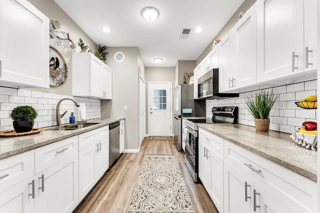 280 W Woodland Dr Unit Ld, Branson, MO 65616 - kitchen with stainless steel appliances, white cabinets, light wood-style flooring, backsplash, and recessed lighting