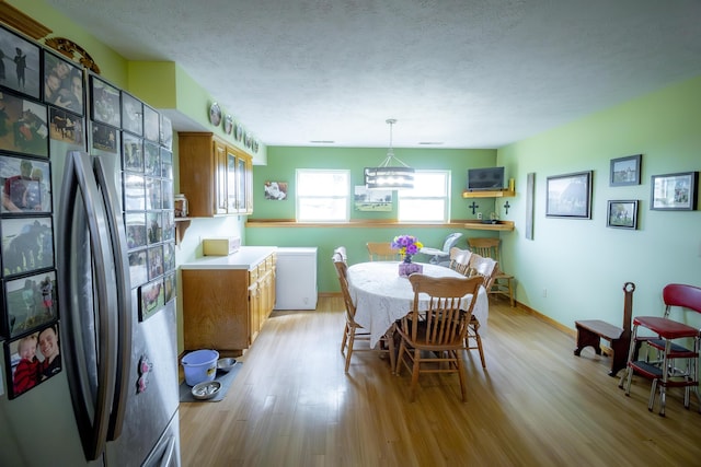 9396 Lawrence Unit 2040, Miller, MO 65707 - dining space featuring light wood-style floors, a textured ceiling, and a chandelier