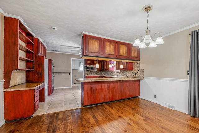 829 W Highland St, Springfield, MO 65807 - kitchen featuring stainless steel microwave, a peninsula, a chandelier, decorative backsplash, and open shelves