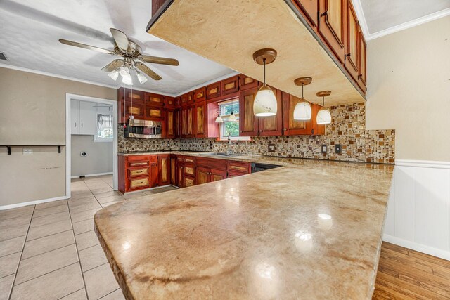 829 W Highland St, Springfield, MO 65807 - kitchen featuring stainless steel microwave, a peninsula, ceiling fan, crown molding, and decorative backsplash