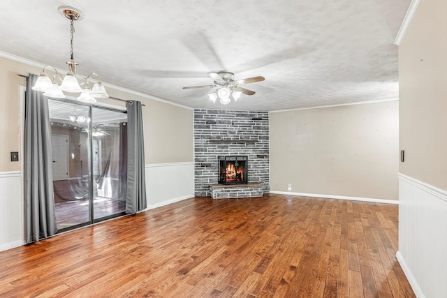 829 W Highland St, Springfield, MO 65807 - unfurnished living room featuring ceiling fan, hardwood / wood-style flooring, a chandelier, a wainscoted wall, and a stone fireplace