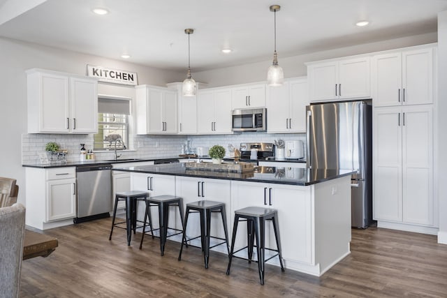 34 Shellie Ln, Branson, MO 65616 - kitchen featuring stainless steel appliances, a center island, white cabinets, dark countertops, and tasteful backsplash