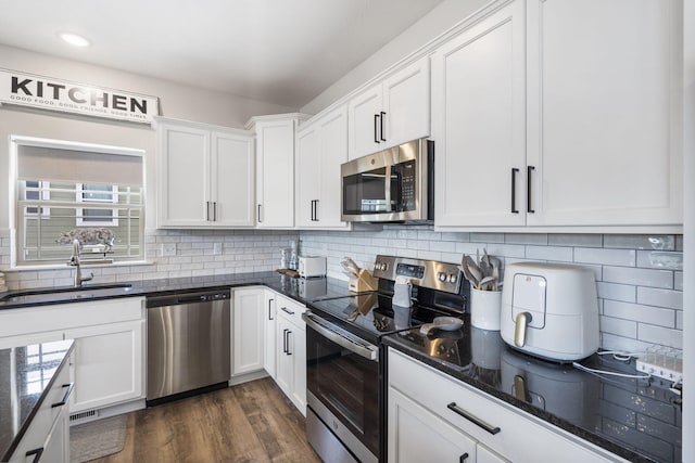 34 Shellie Ln, Branson, MO 65616 - kitchen with appliances with stainless steel finishes, white cabinetry, dark wood-style floors, decorative backsplash, and recessed lighting