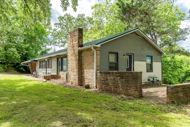 705 Preacher Roe Blvd, West Plains, MO 65775 - back of house with a chimney, a yard, stone siding, and a metal roof
