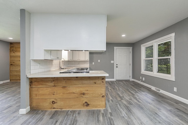 3512 S Ferguson Ave, Springfield, MO 65807 - kitchen with wood finished floors, a peninsula, light countertops, decorative backsplash, and white cabinetry