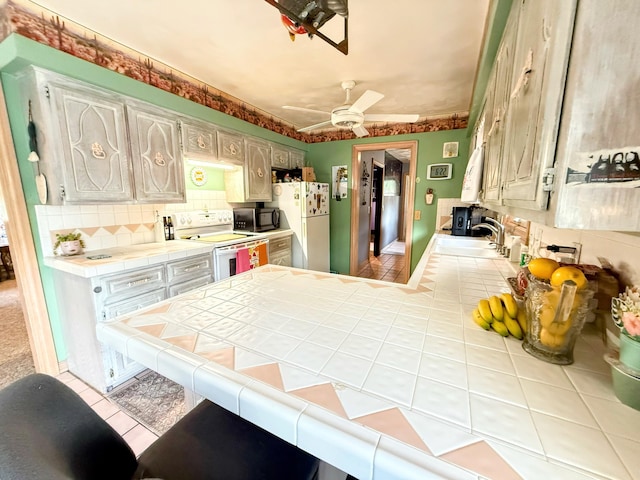 6424 W Farm Rd Unit 140, Springfield, MO 65802 - kitchen featuring tile counters, white appliances, tile patterned floors, a peninsula, and tasteful backsplash