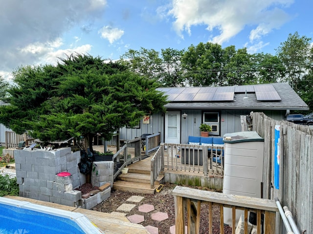 6424 W Farm Rd Unit 140, Springfield, MO 65802 - back of property with roof mounted solar panels, a deck, board and batten siding, and a shingled roof